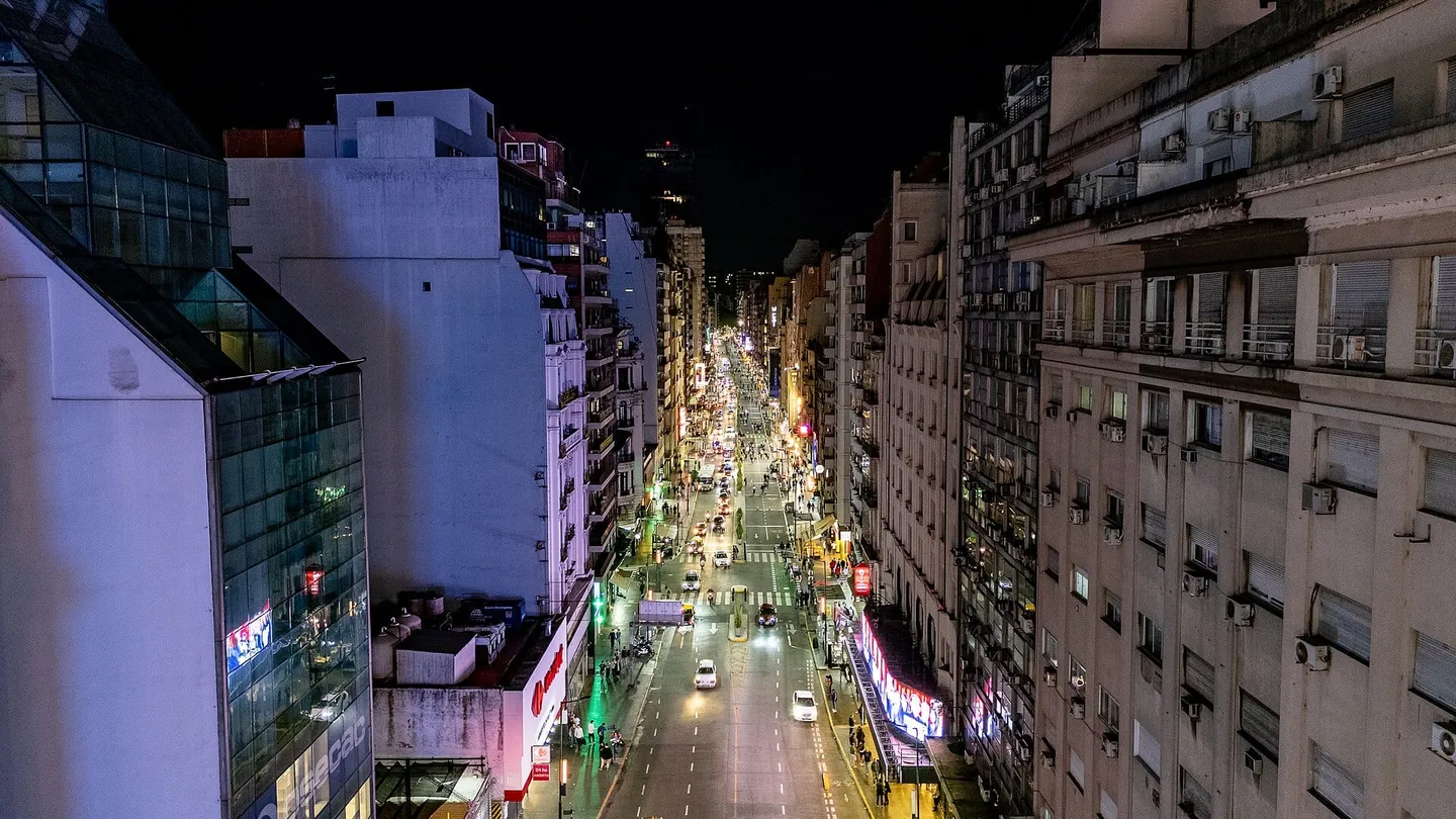 Vista aérea nocturna del cruce de la Avenida 9 de Julio con la Avenida Corrientes, en Buenos Aires, con el Obelisco iluminado