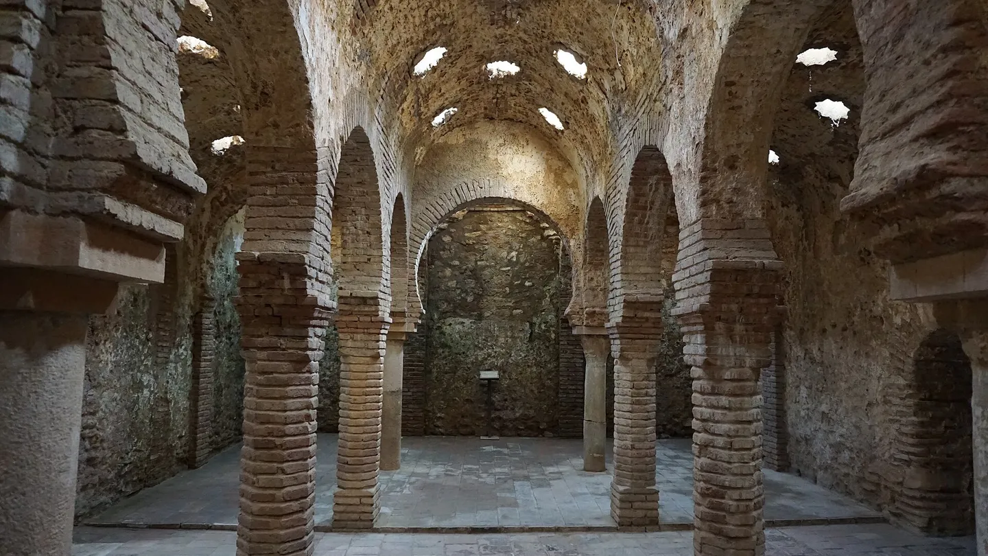Sala central de los baños árabes de Ronda, con arcos de herradura sobre columnas de ladrillo y lucernarios en forma de estrella en la bóveda