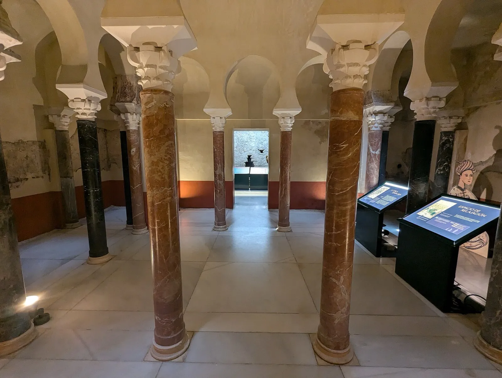 Sala de los baños califales de Córdoba, con columnas, arcos de herradura y paneles del museo