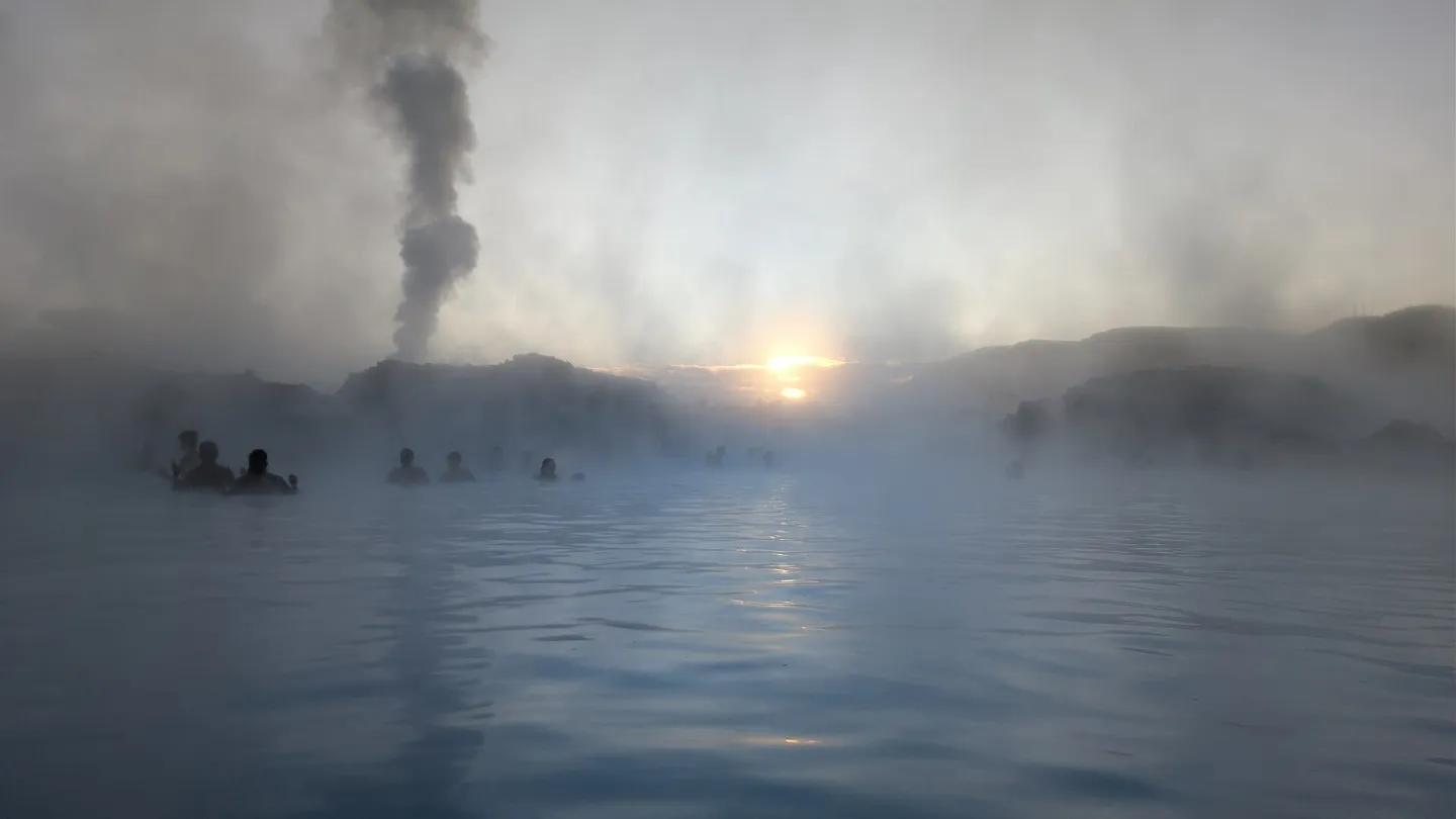 Amanecer en la Blue Lagoon, en Islandia, con vapor sobre el agua azul lechosa y bañistas a lo lejos