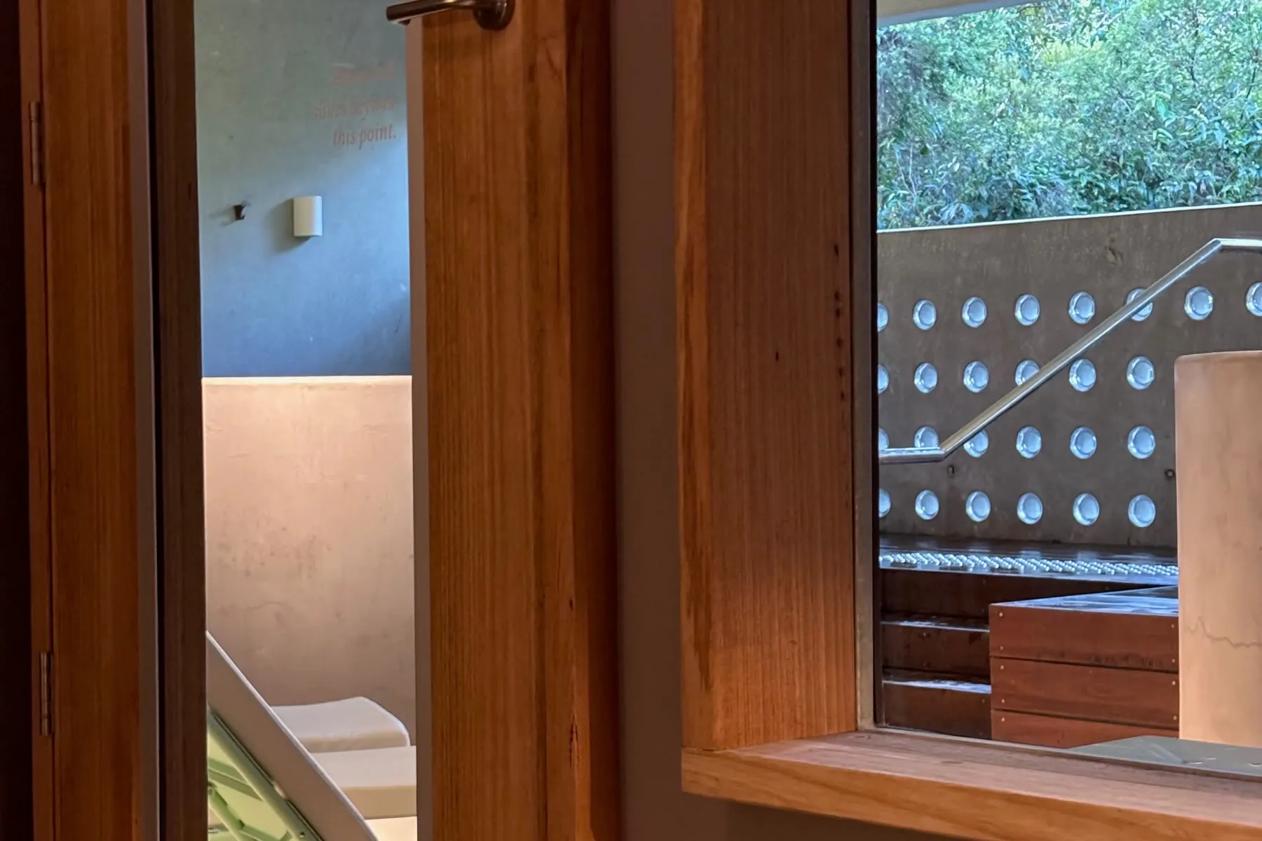 Ventana de madera de la Comma, con vista al área de baños y a la vegetación