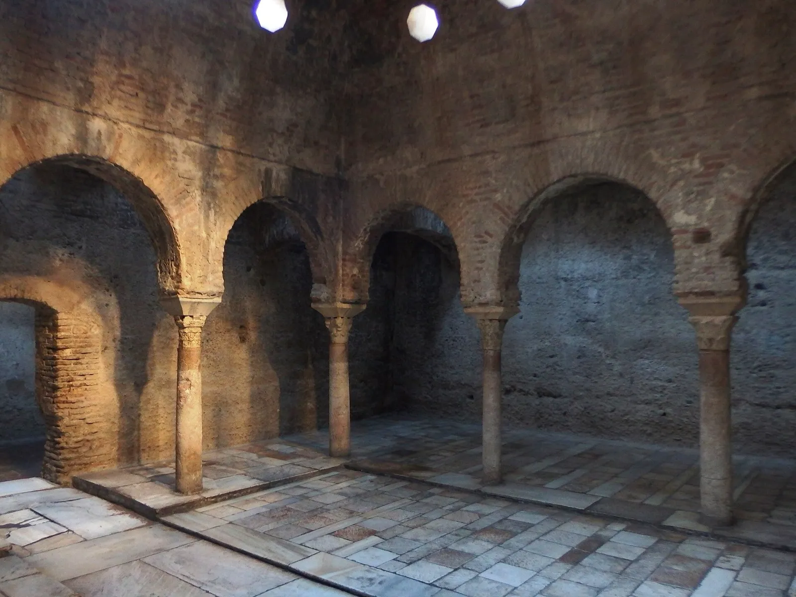 Sala templada del Bañuelo de Granada, con arcos de herradura sobre columnas y suelo de losas de piedra