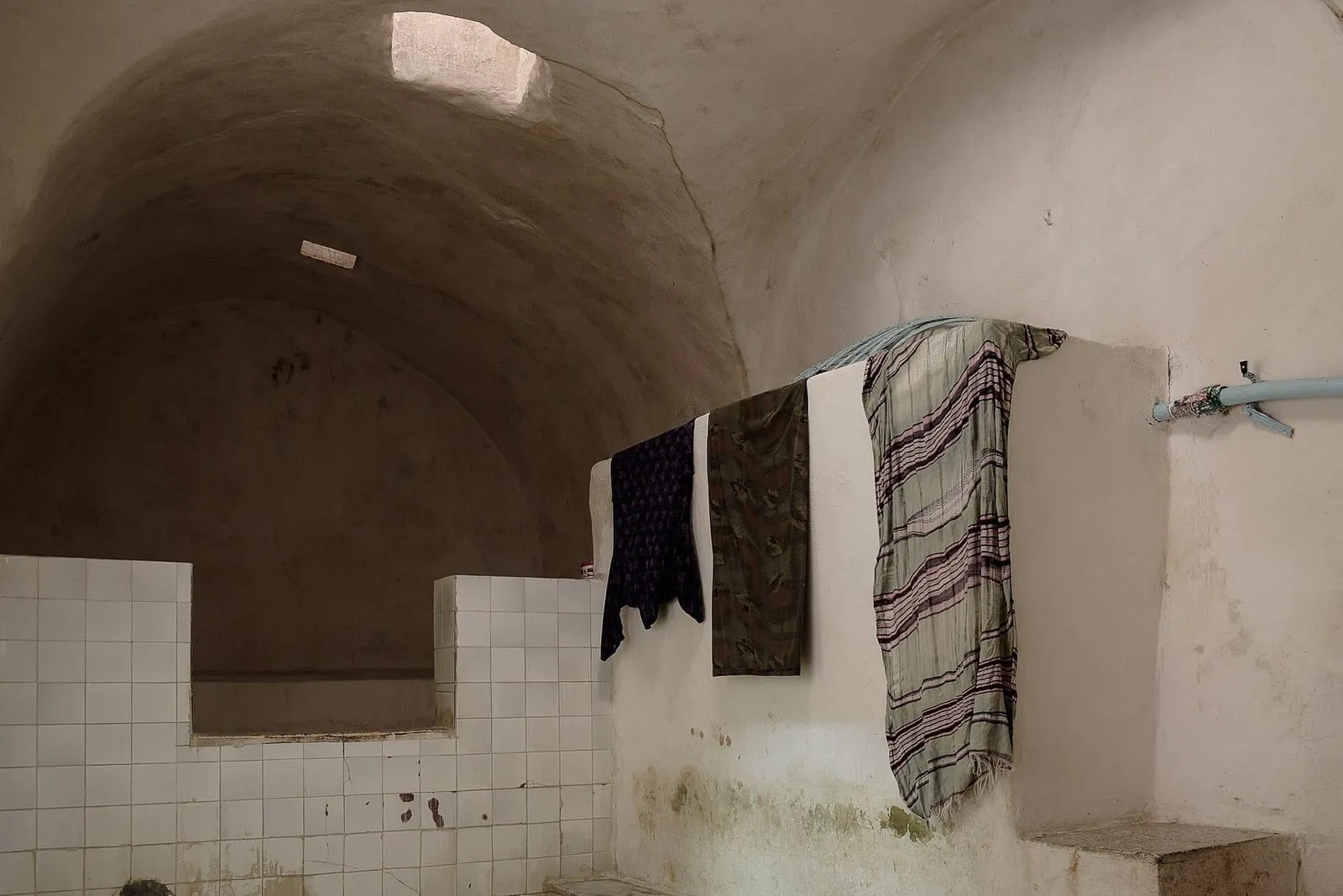 Caldarium del hammam Zeitouni, en Túnez, con paredes blancas, nichos abovedados y una tina de piedra