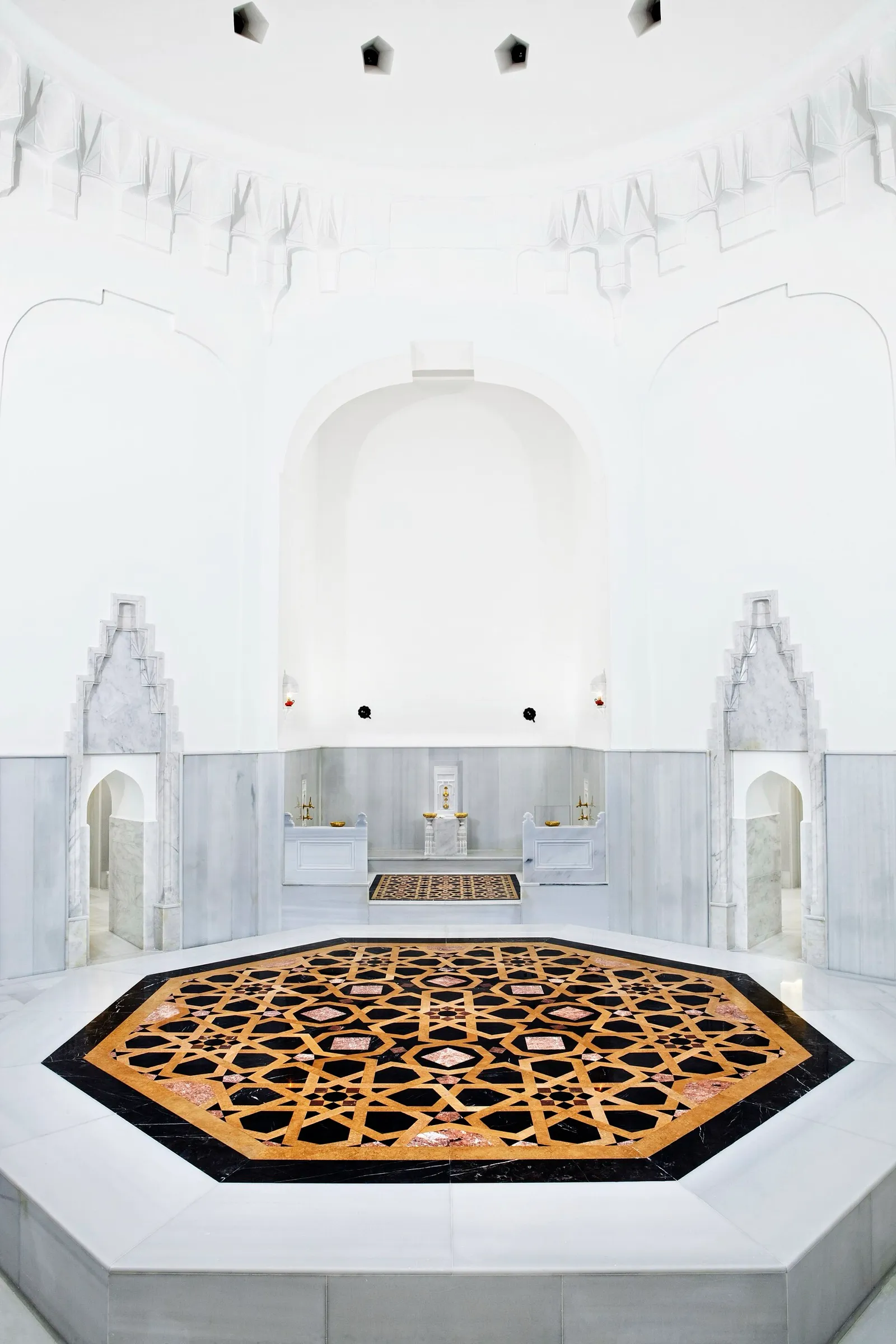 Sala caliente del Hürrem Sultan Hamamı, en Estambul, con muros de mármol blanco, nichos de lavado y una plataforma octogonal de mármol con incrustaciones al centro
