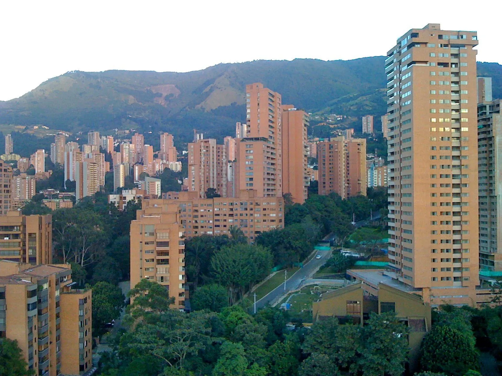 Vista de El Poblado, en Medellín, con edificios de ladrillo entre árboles y las montañas al fondo