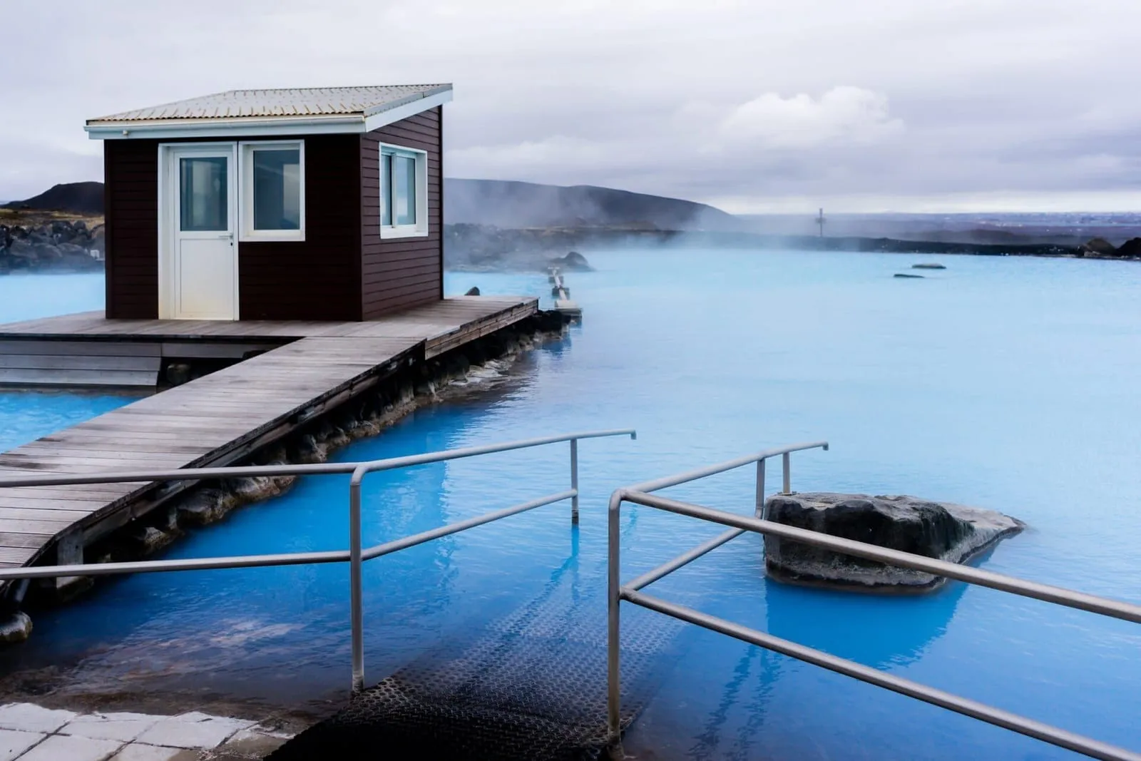 Laguna azul turquesa de los Mývatn Nature Baths, con deck de madera, barandal y vapor sobre el agua