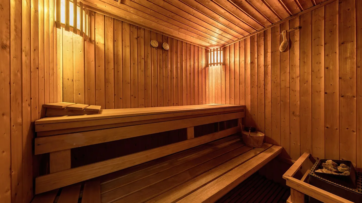Interior de sauna revestido de madera clara, con bancas en dos niveles y luz cálida, en Luang Prabang, Laos