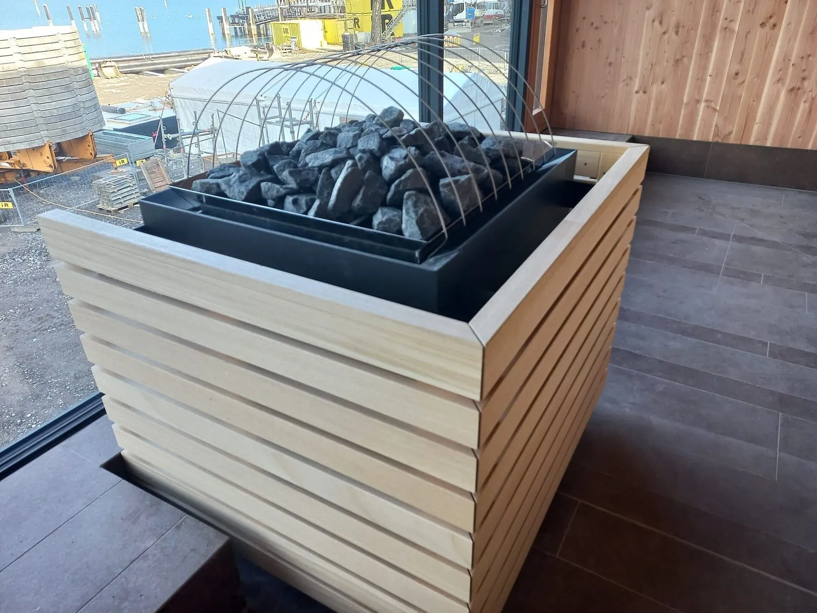 Calentador de sauna con piedras, envuelto en listones de madera, en un sauna todavía en obra en Bregenz