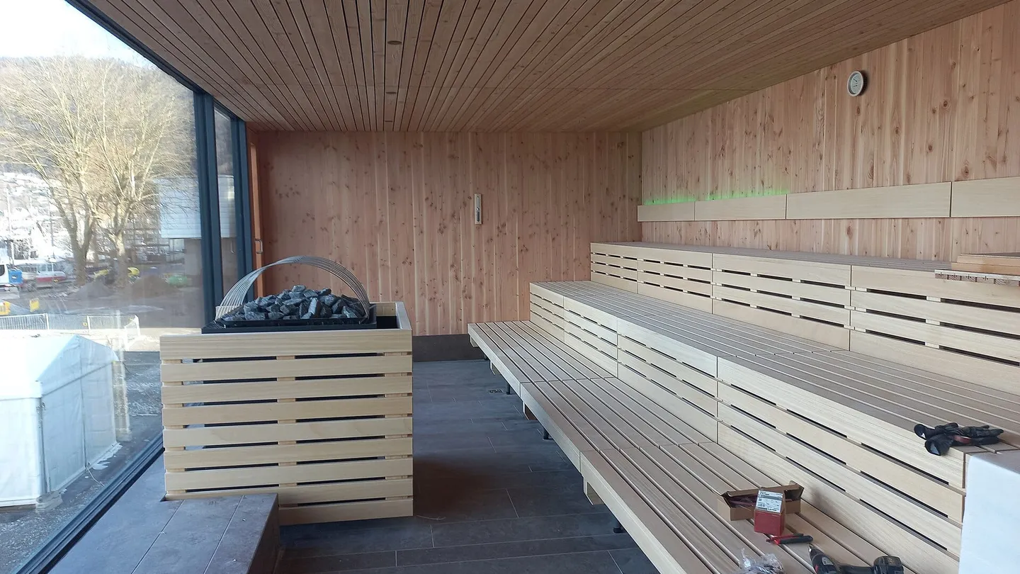 Sauna en construcción en el Seebad de Bregenz, Austria, con bancas de madera clara, calentador y ventana al lago