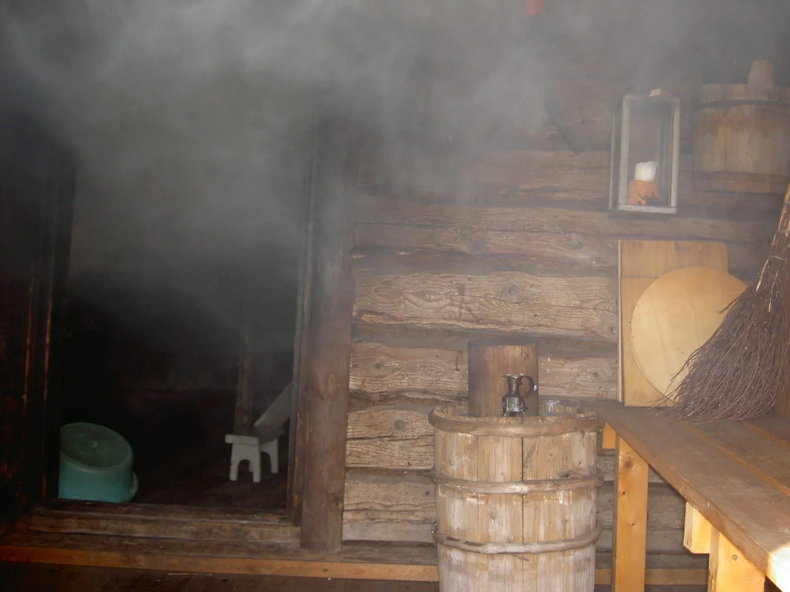 Interior de un sauna de humo finlandés en Uusikaupunki, con vapor en el aire, bancas de madera y un balde
