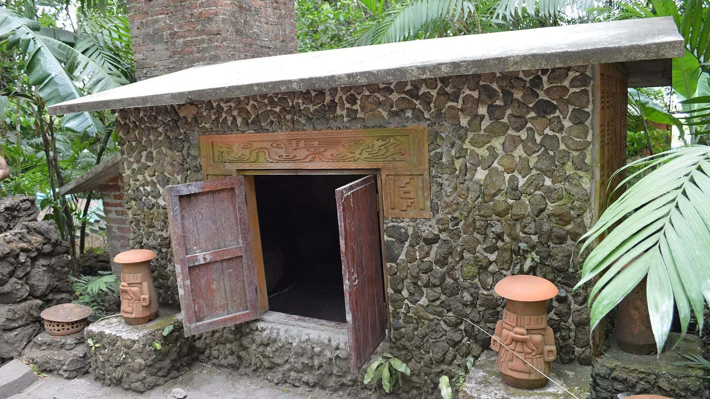 Temazcal de piedra con techo bajo, puerta de madera angosta y relieve pintado sobre la entrada, en el parque de Nanciyaga, en Catemaco, Veracruz